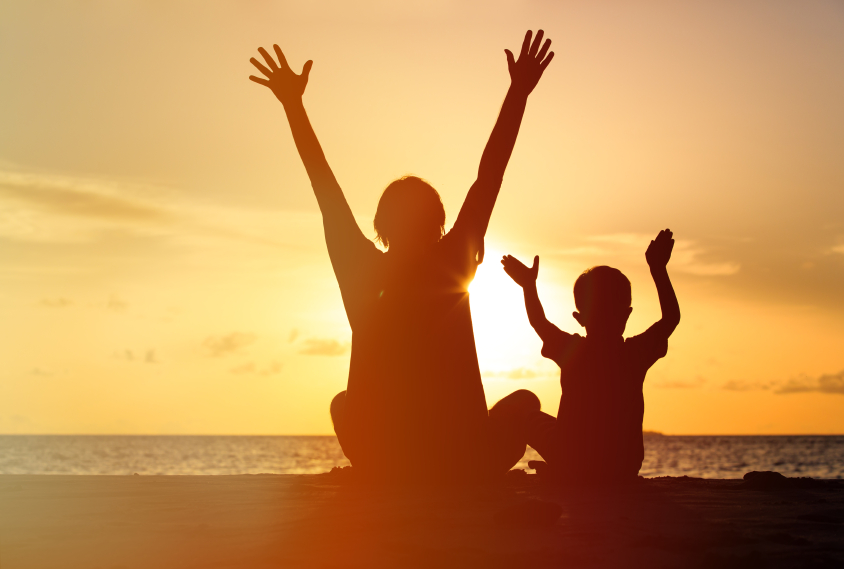 Silhouette of happy father and son at sunset beach